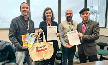 Quatro representantes posam com cartilhas e sacola da campanha Brasil Sem Trabalho Infantil após assinatura de parceria.