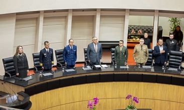 Mesa de honra com seis autoridades em pé durante evento