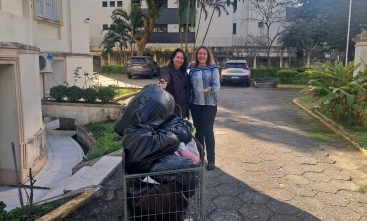 Duas mulheres sorriem para a foto diante de um carrinho cheio de doações