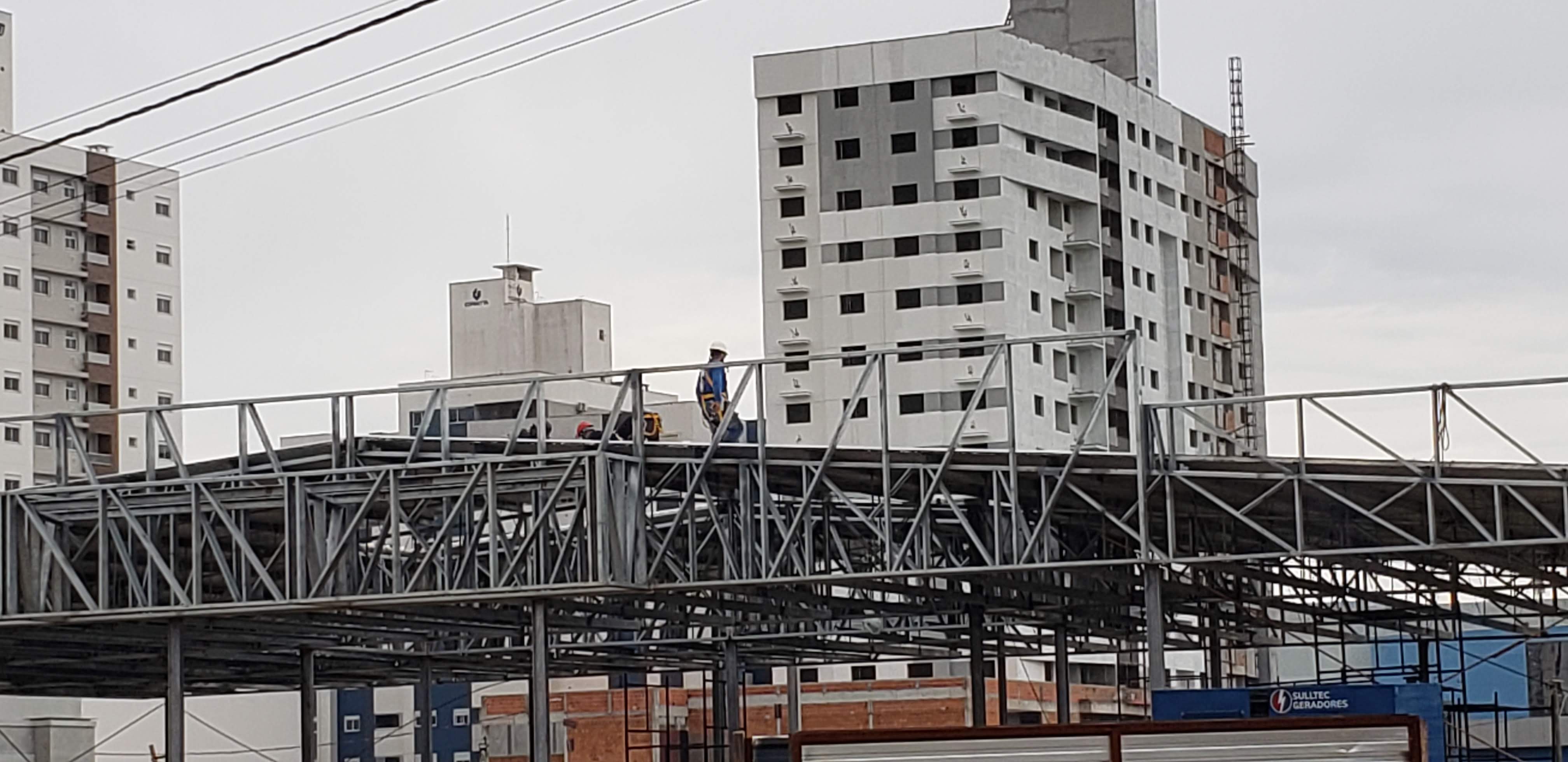 Estrutura metálica da cobertura do telhado em execução com 2 homens trabalhando