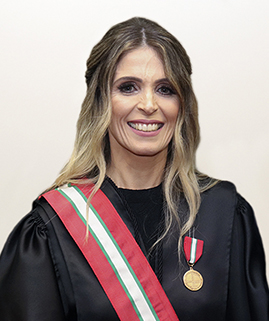 Foto de uma mulher branca vestida de beca e uma medalha no peito