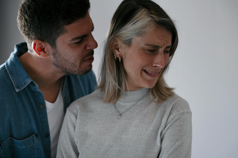 Foto de um homem branco brigando com uma mulher branca. Ela está triste.