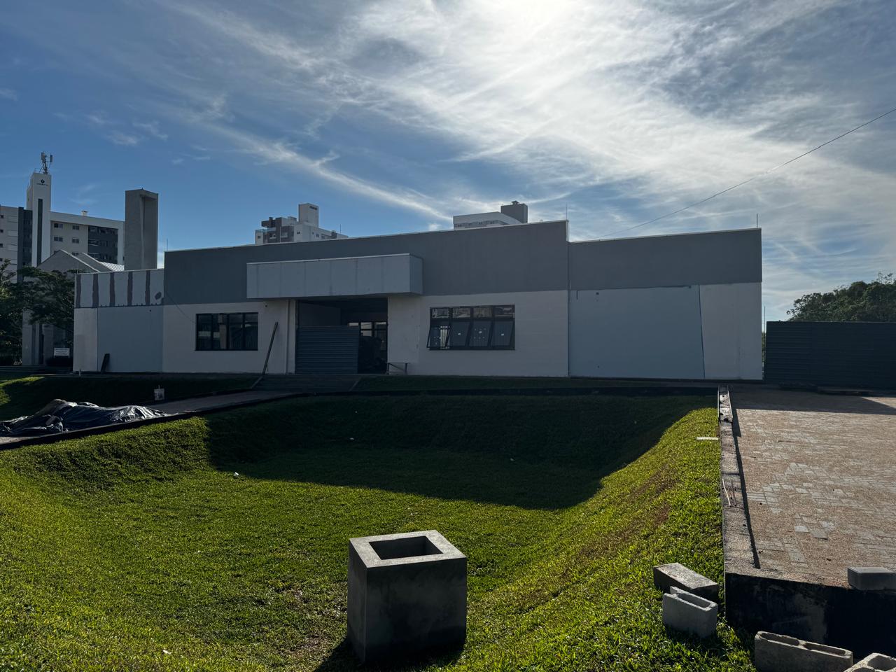 Foto - Fachada frente do prédio com grama plantada na bacia de amortecimento pluvial