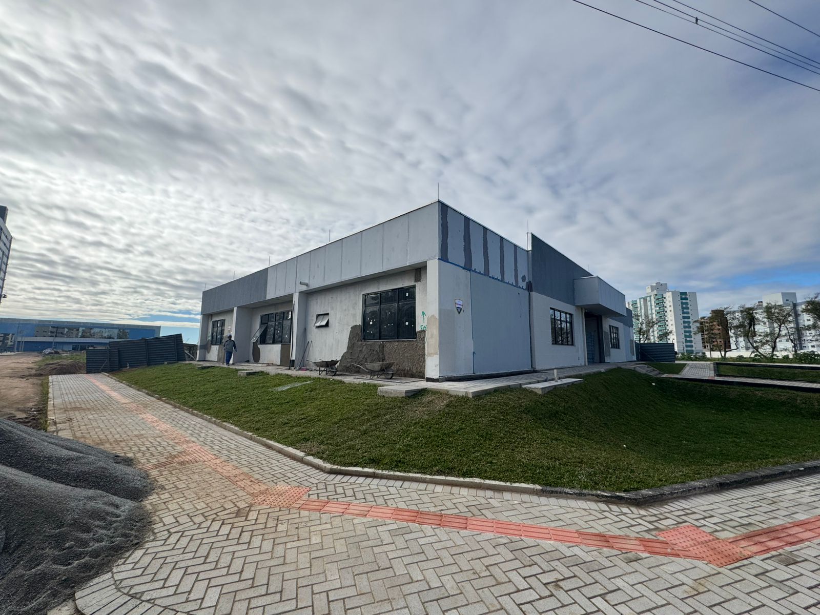 Foto - Vista externa do prédio com calçada e grama no terreno.