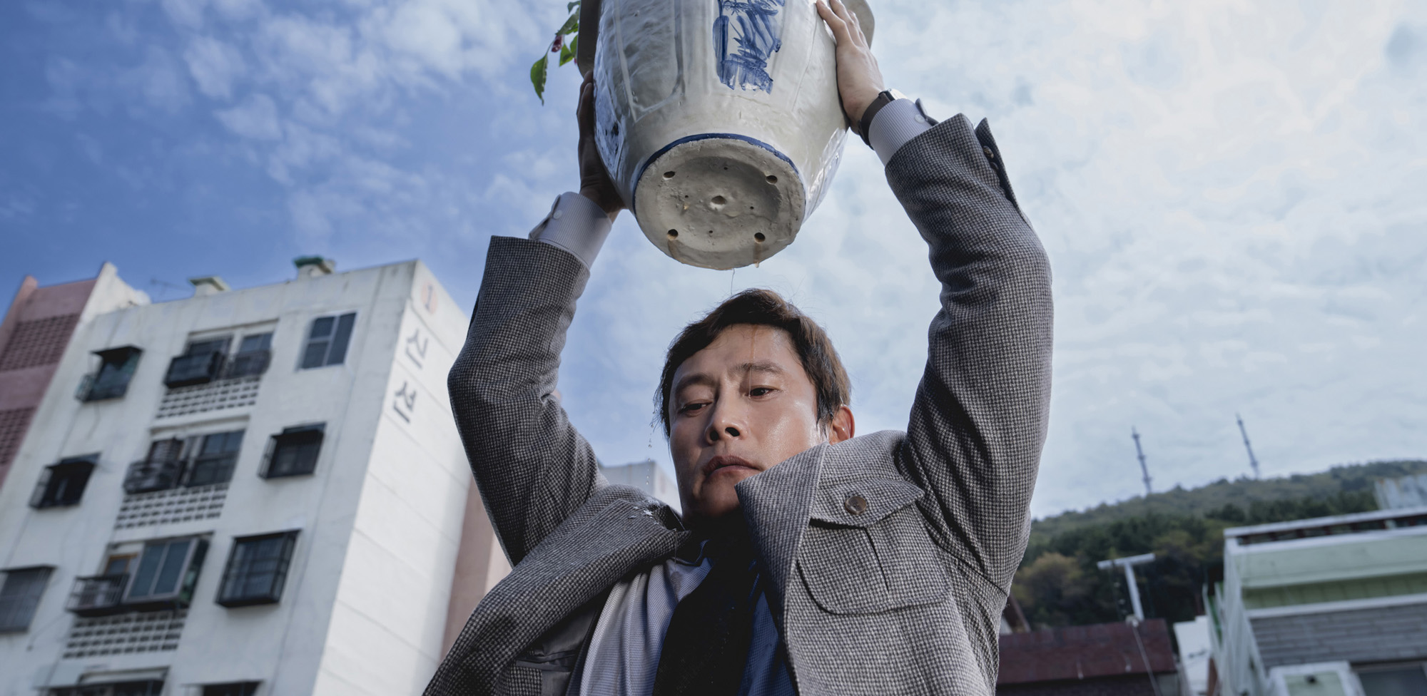 Para todos verem: Banner em que há um homem olhando para baixo e segurando um vaso de planta em cima da sua cabeça. 