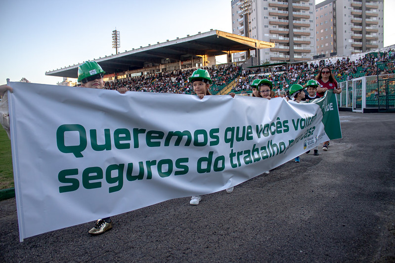 crianças segurando uma faixa verde e branca