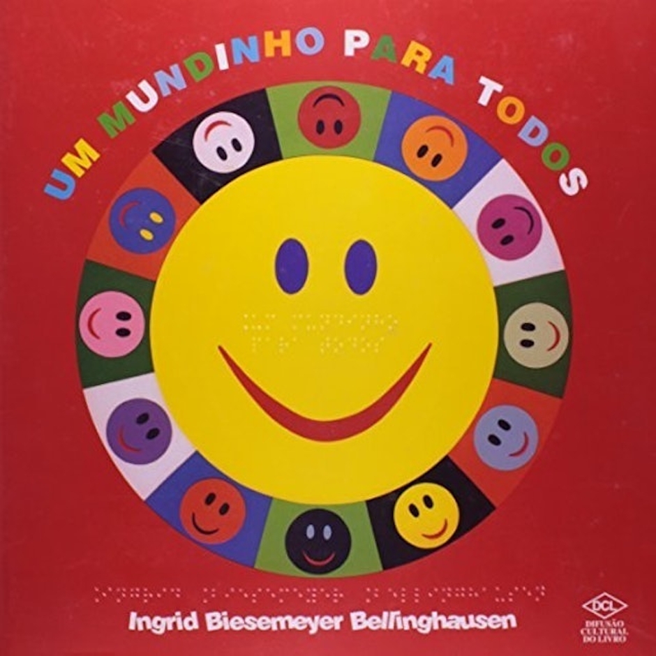 Para todos verem: Texto: “Um Mundinho para Todos. Ingrid Biesemeyer Bellinghausen”. Ilustração: Capa do livro vermelha em que no centro há uma carinha feliz amarela sorrindo. Ao redor há várias carinhas felizes coloridas sorrindo.
