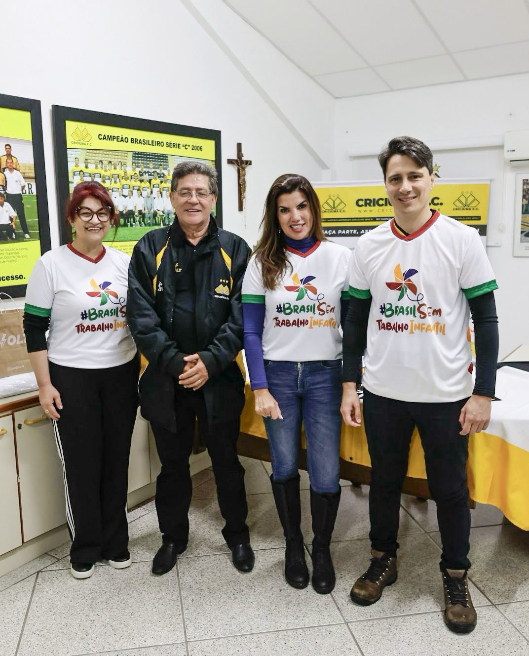 Quatro pessoas, sendo uma mulher ruiva de óculos, um homem de jaqueta preta, cabelo grisalho e óculos,uma mulher de cabelos longos e um homem alto de cabelos castanhos