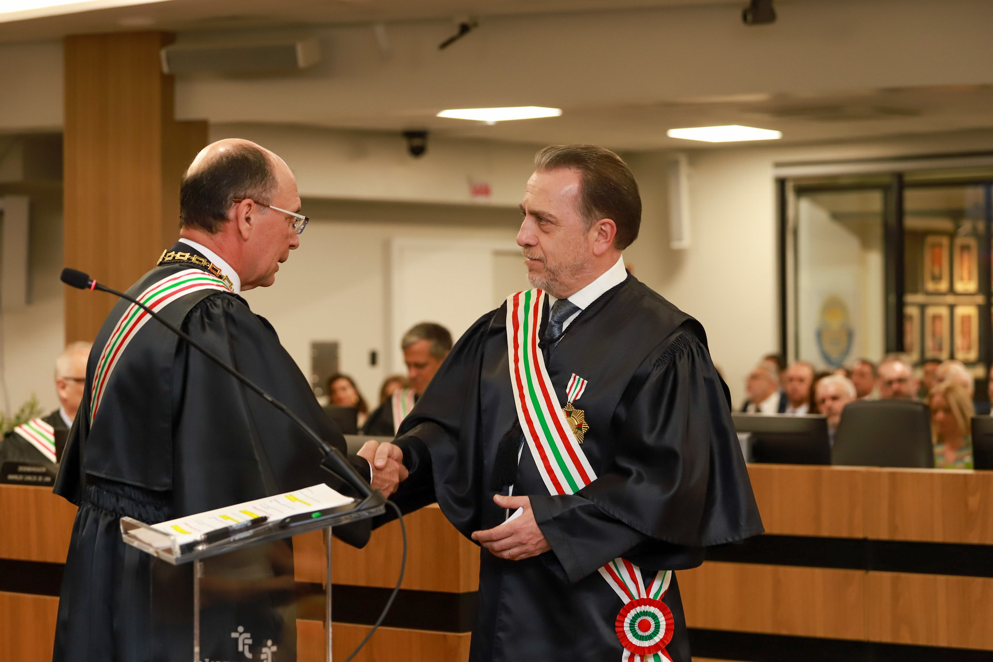 Dois homens vestindo toga se cumprimentam