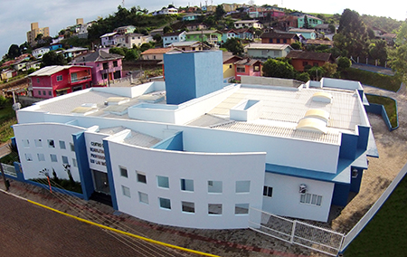 Fotografia aérea de um prédio de grandes proporções, nas cores branca e azul