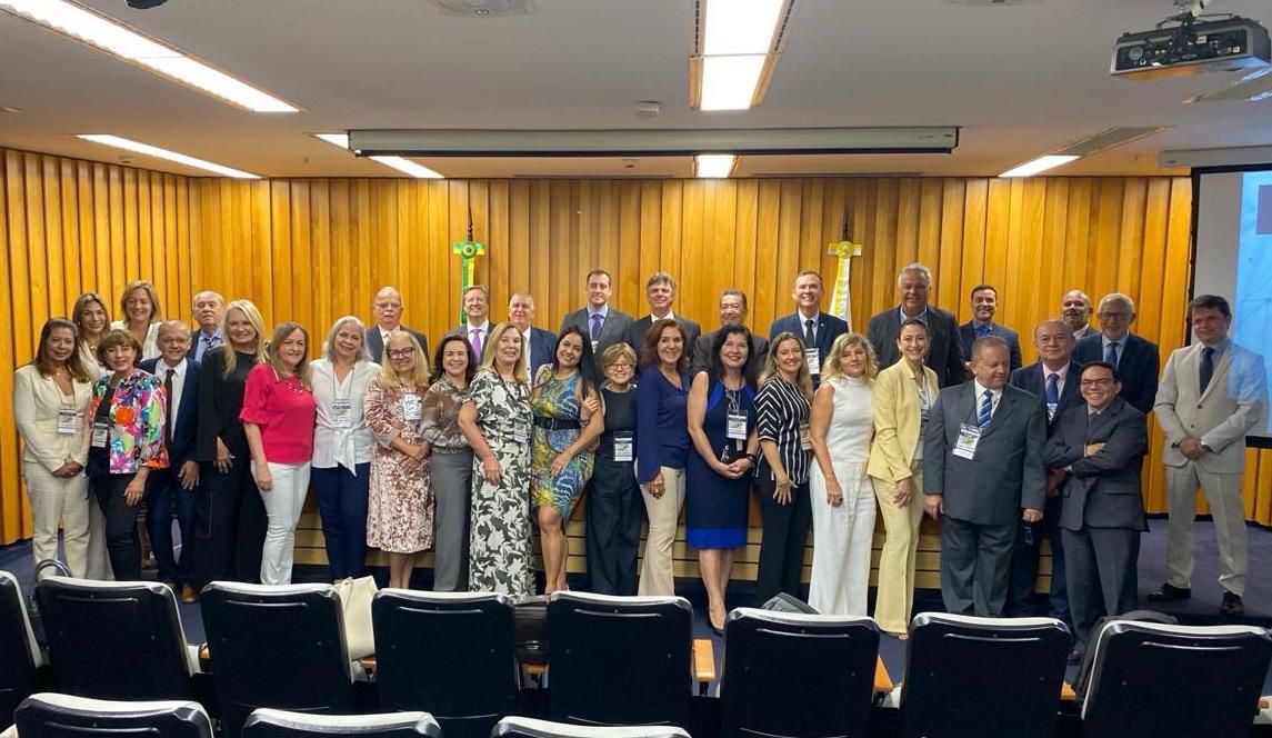 um grupo de pessoas, homens e mulheres, em pé posando para a foto em um auditório