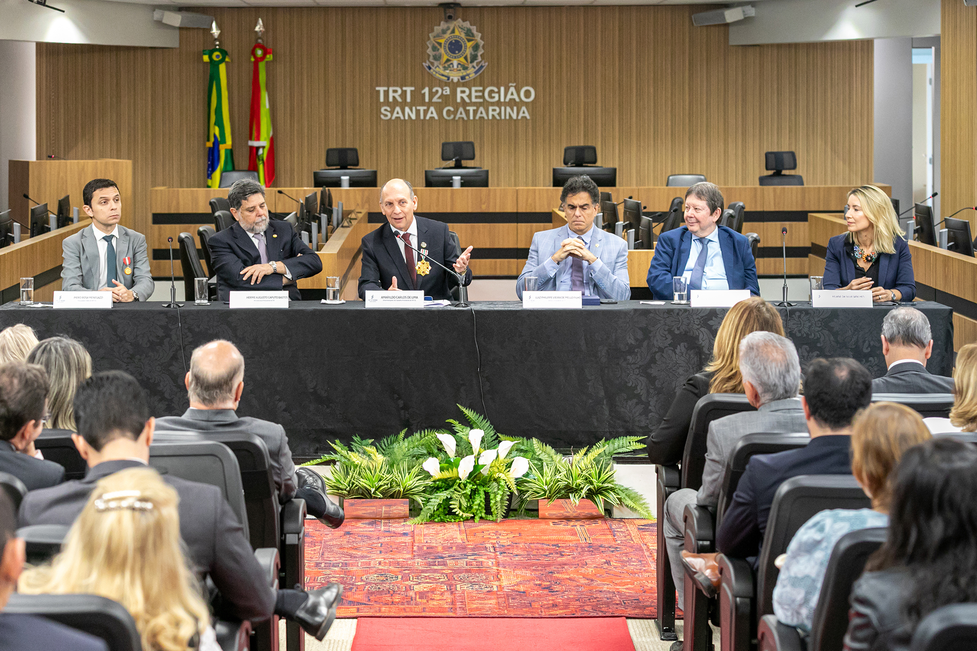 Seis pessoas sentadas à mesa de abertura, coberta por um pano preto. Ao fundo, o brasão da República.