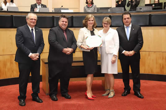 Desembargadora Leiria com deputados na ALESC, sendo homenageada