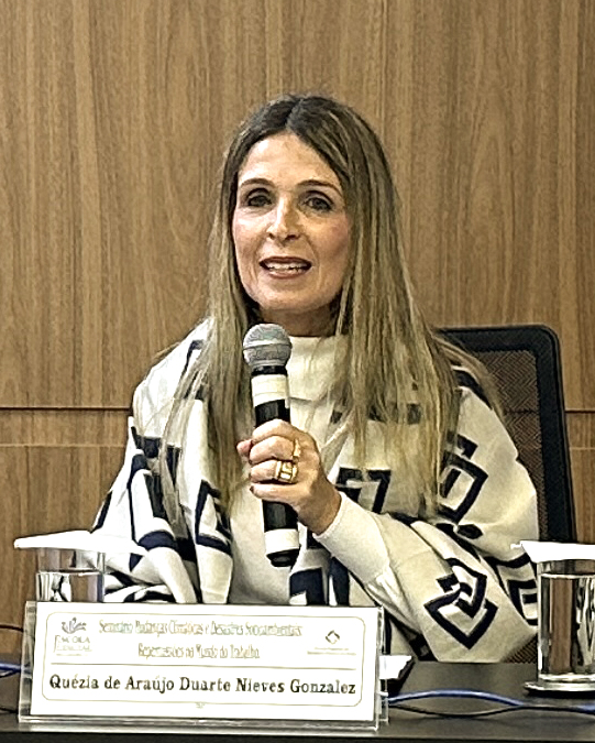 Mulher de cabelos claros falando ao microfone