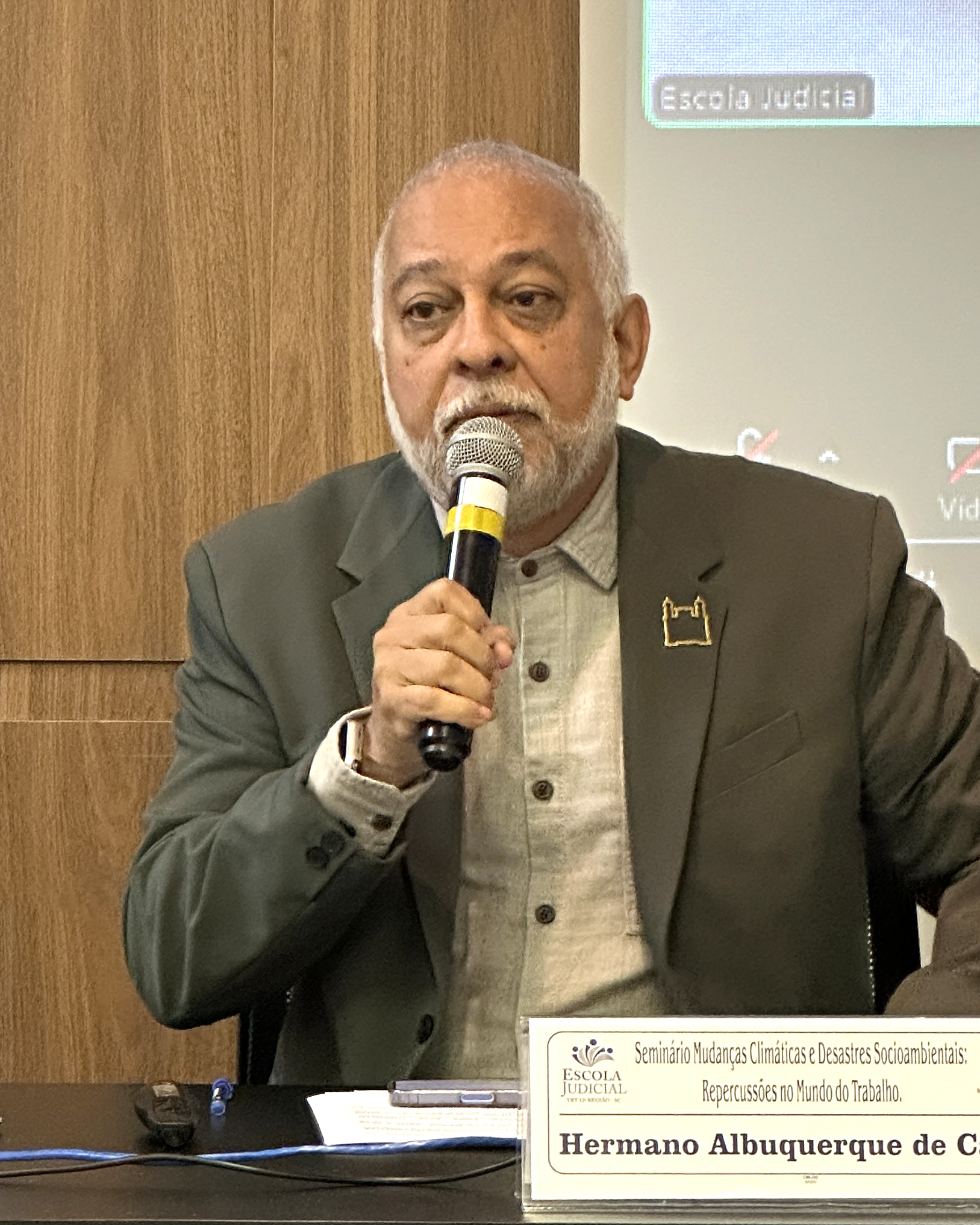 Homem de paletó, grisalho, negro, fala ao microfone