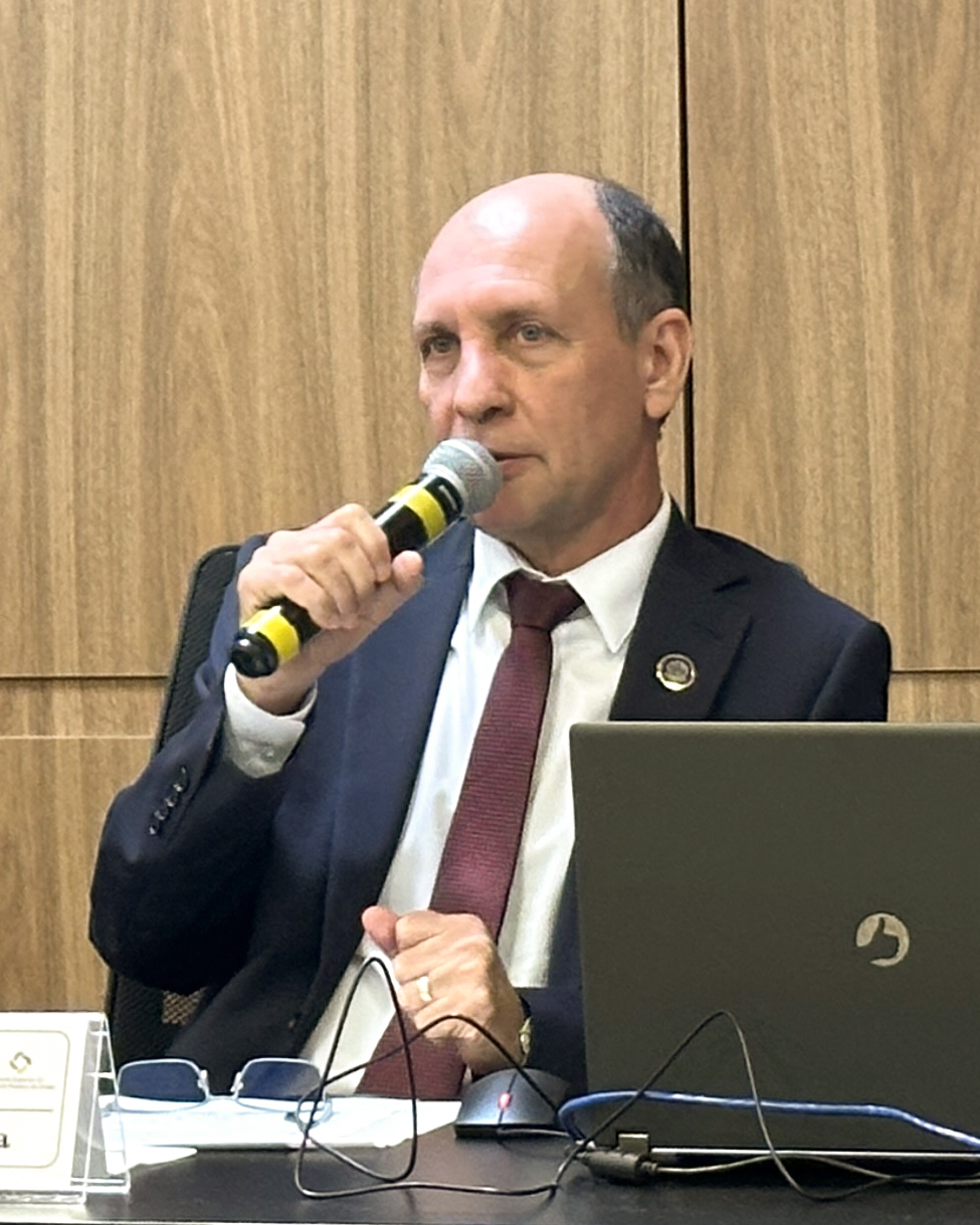 Homem calvo, de terno, fala ao microfone
