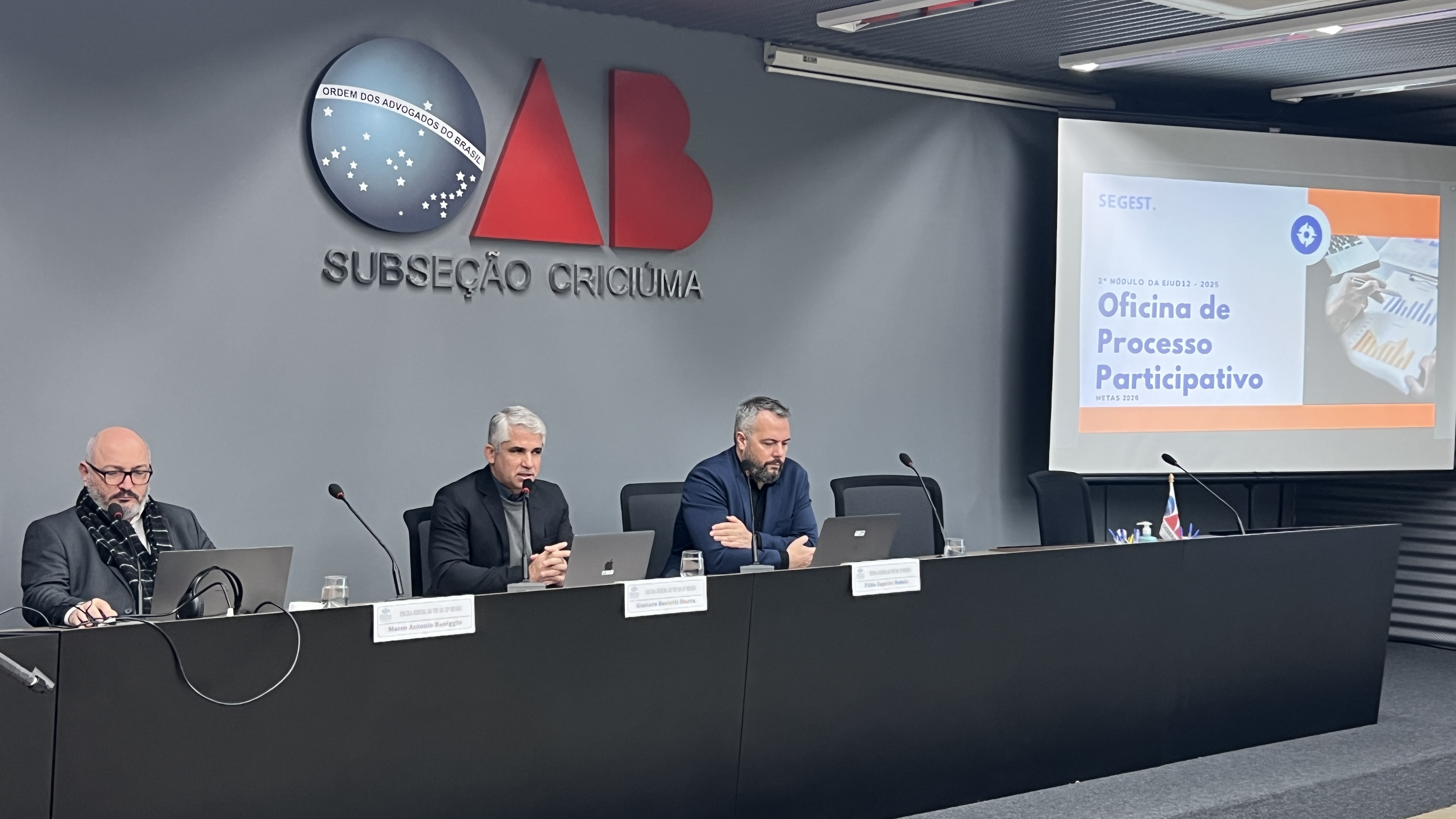 Três homens estão sentados e fazendo uma palestra