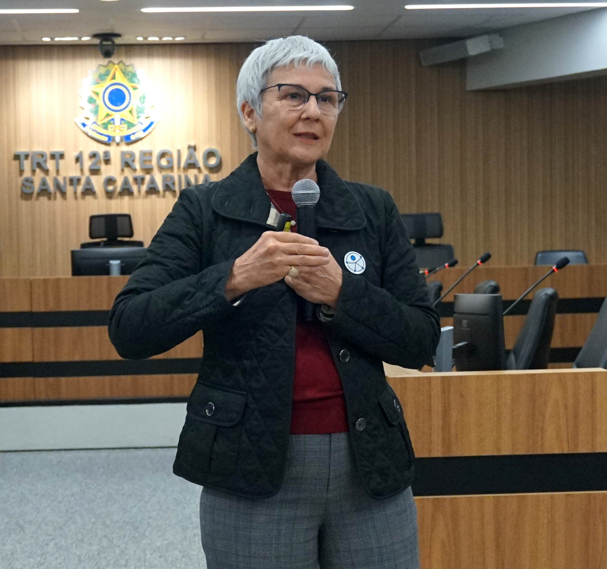 Mulher de cabelos grisalhos falando ao microfone