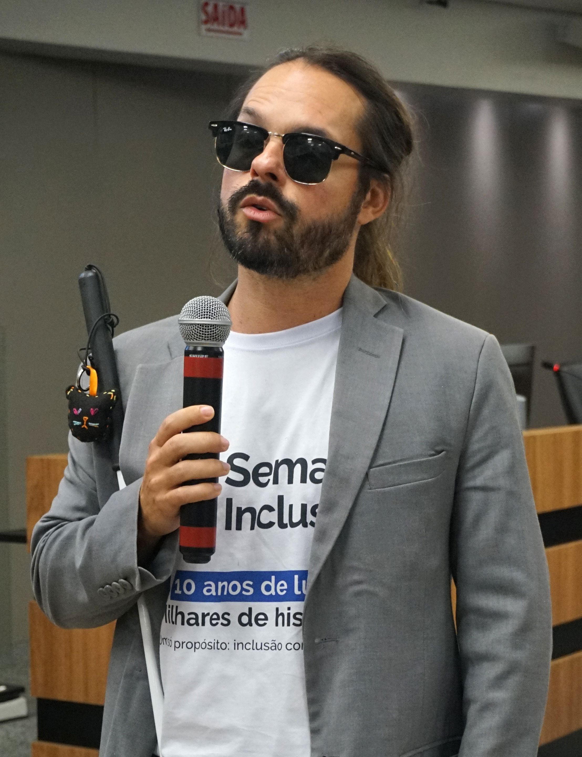 Homem de óculos escuros falando ao microfone