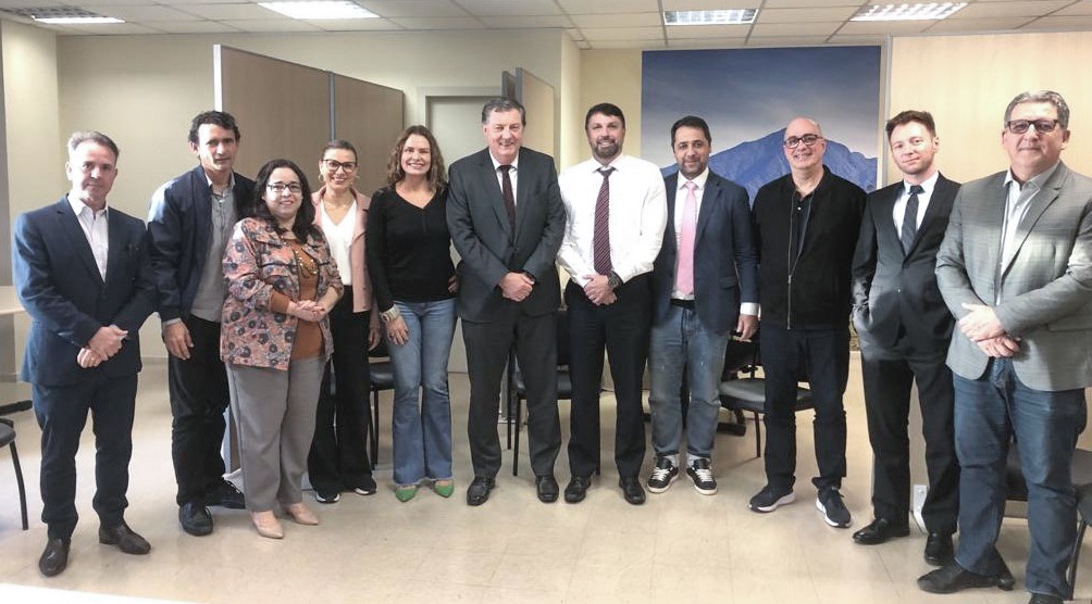 Oito homens e três mulheres estão em pé, sorrindo e posando para a foto