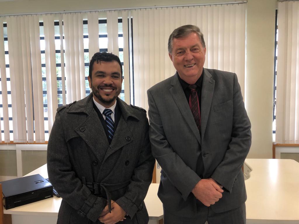 Dois homens em pé sorriem e posam para foto