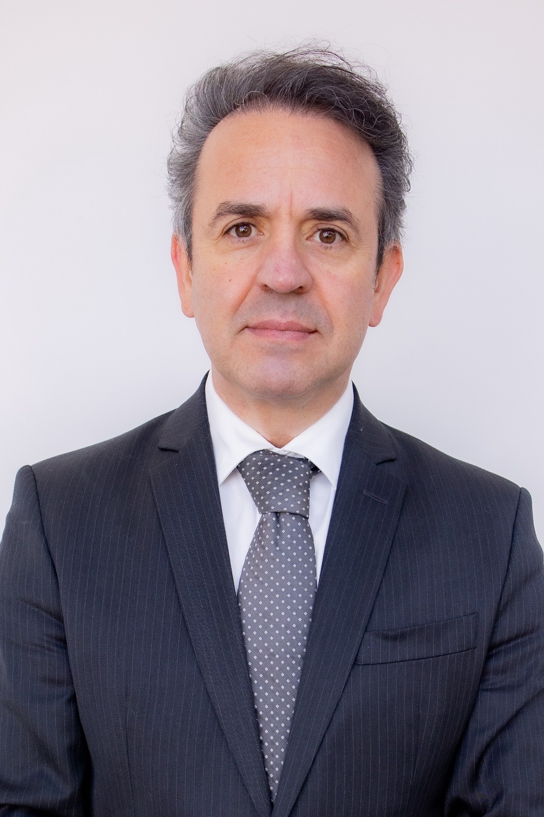 Homem de cerca de 50 anos, branco, vestindo terno escuro, em foto 3x4