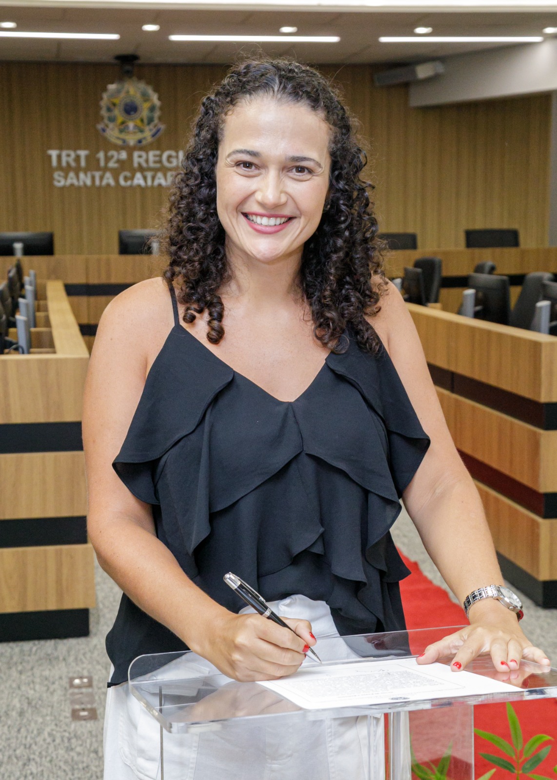 Mulher posa sorrindo assinando termo de posse