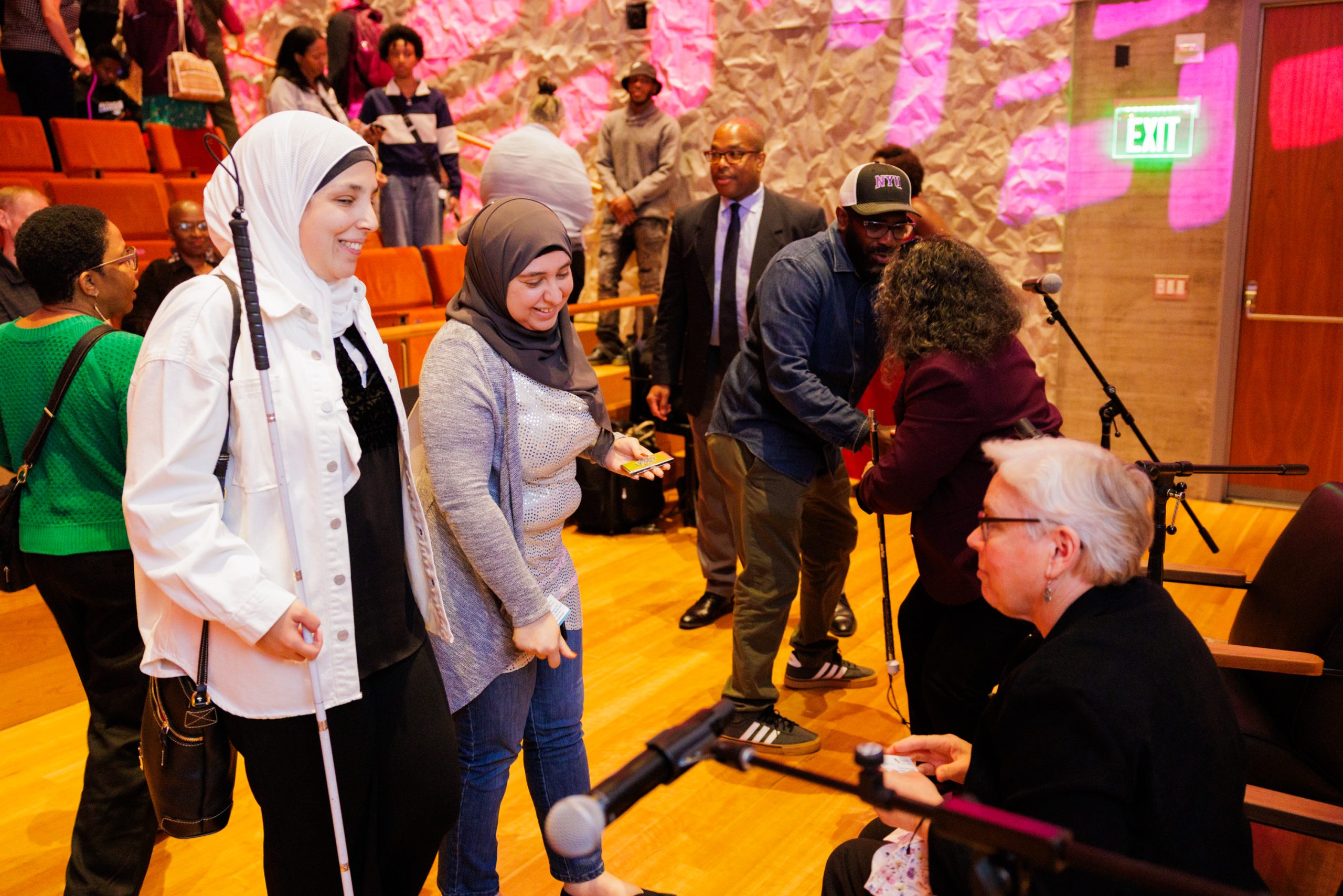Para todos verem: Imagem em que há várias pessoas com e sem deficiência interagindo em um auditório.