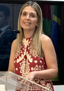 Mulher branca, com cabelo loiro, fala ao microfone