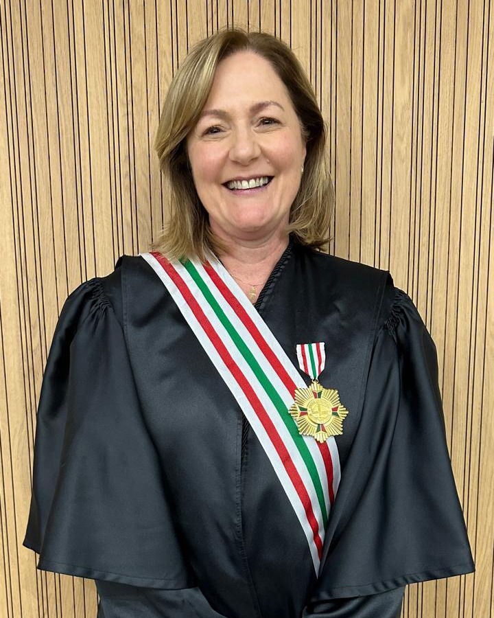 Mulher loira, de cabelos médio, de toga, sorrindo 