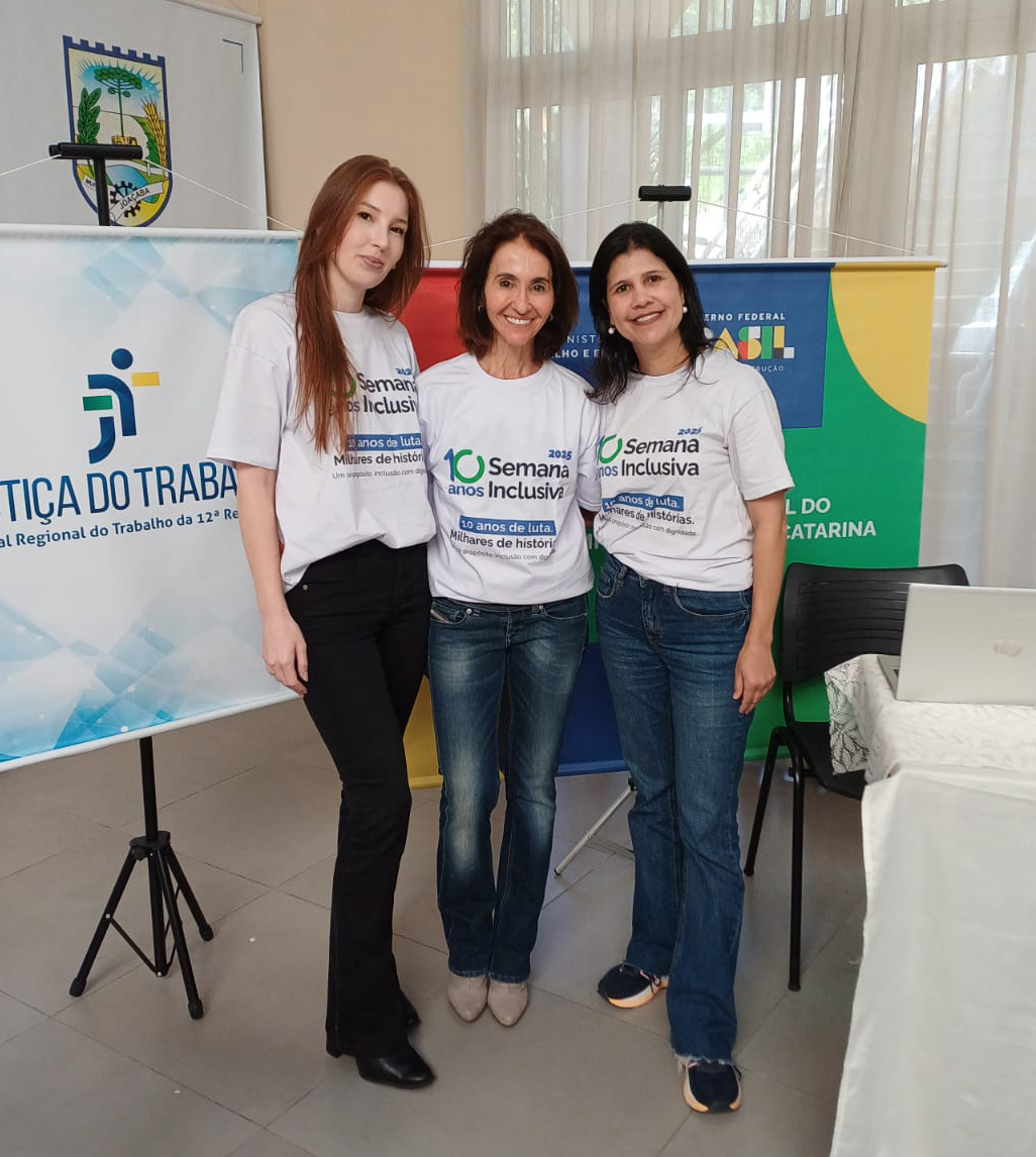 Fotografia com três mulheres, de pé, sorrindo para a câmera