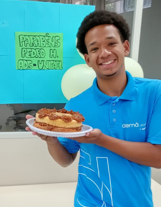 Jovem sorrindo e segurando um bolo