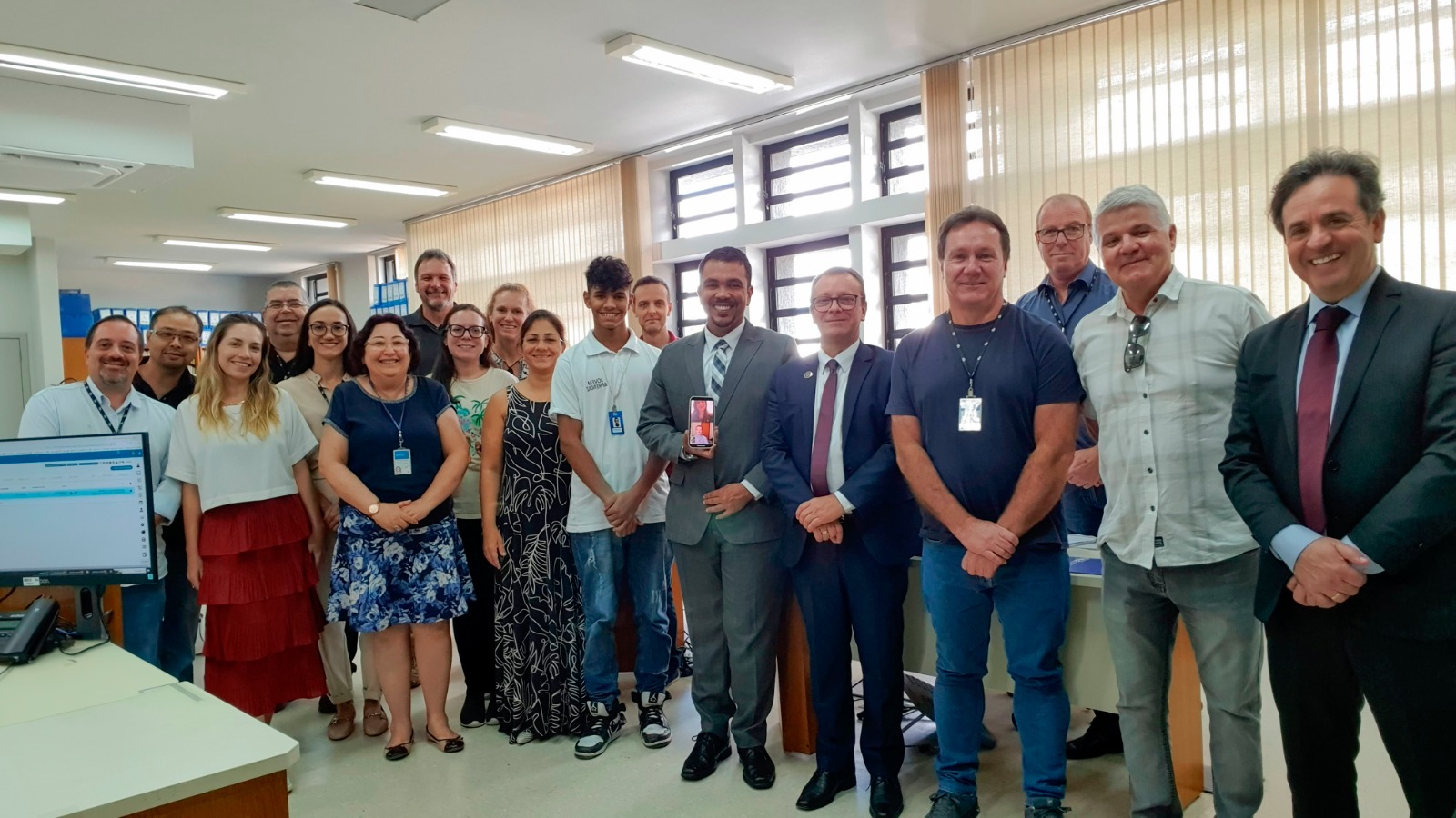 Fotografia de um grupo de dezoito pessoas em pé sorrindo para a foto