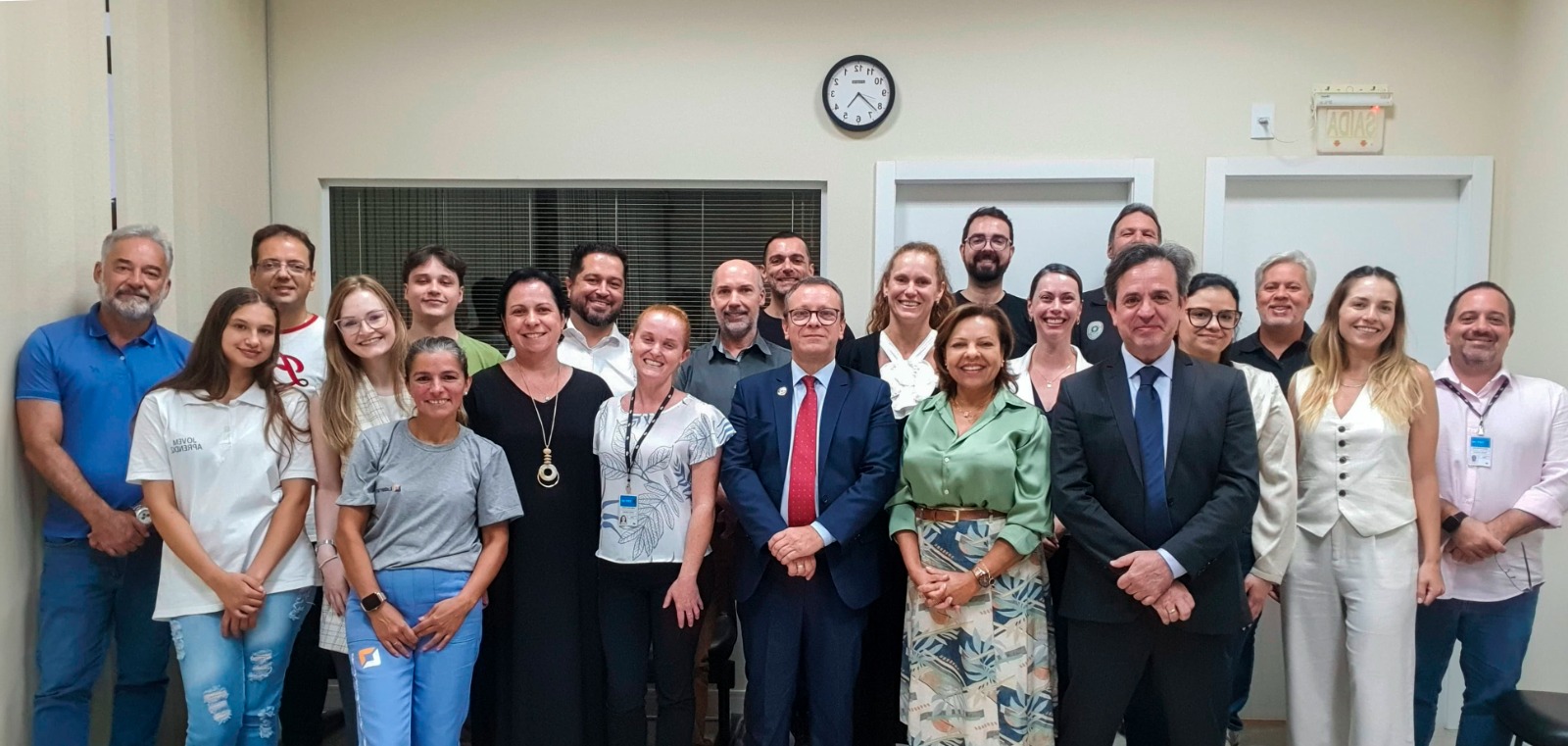 Fotografia de um grupo de vinte e duas pessoas em pé, sorrindo para a foto