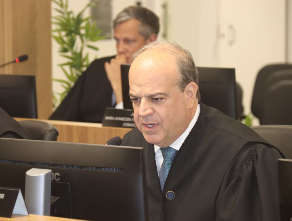 Foto fechada em um homem calvo, de toga, falando e olhando para um monitor