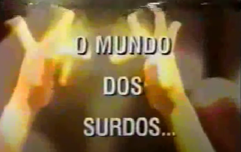 Para todos verem: Texto: "O Mundo dos Surdos...". Ilustração: Banner em que há duas mãos.