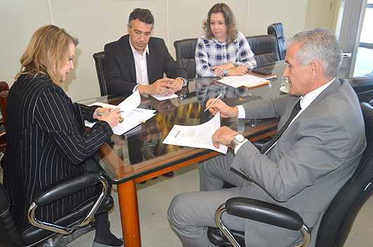 eecretária de Educação, Simone Schramm e o  desembargador Roberto Guglielmetto sentadoa à mesa durante assinatura do termo