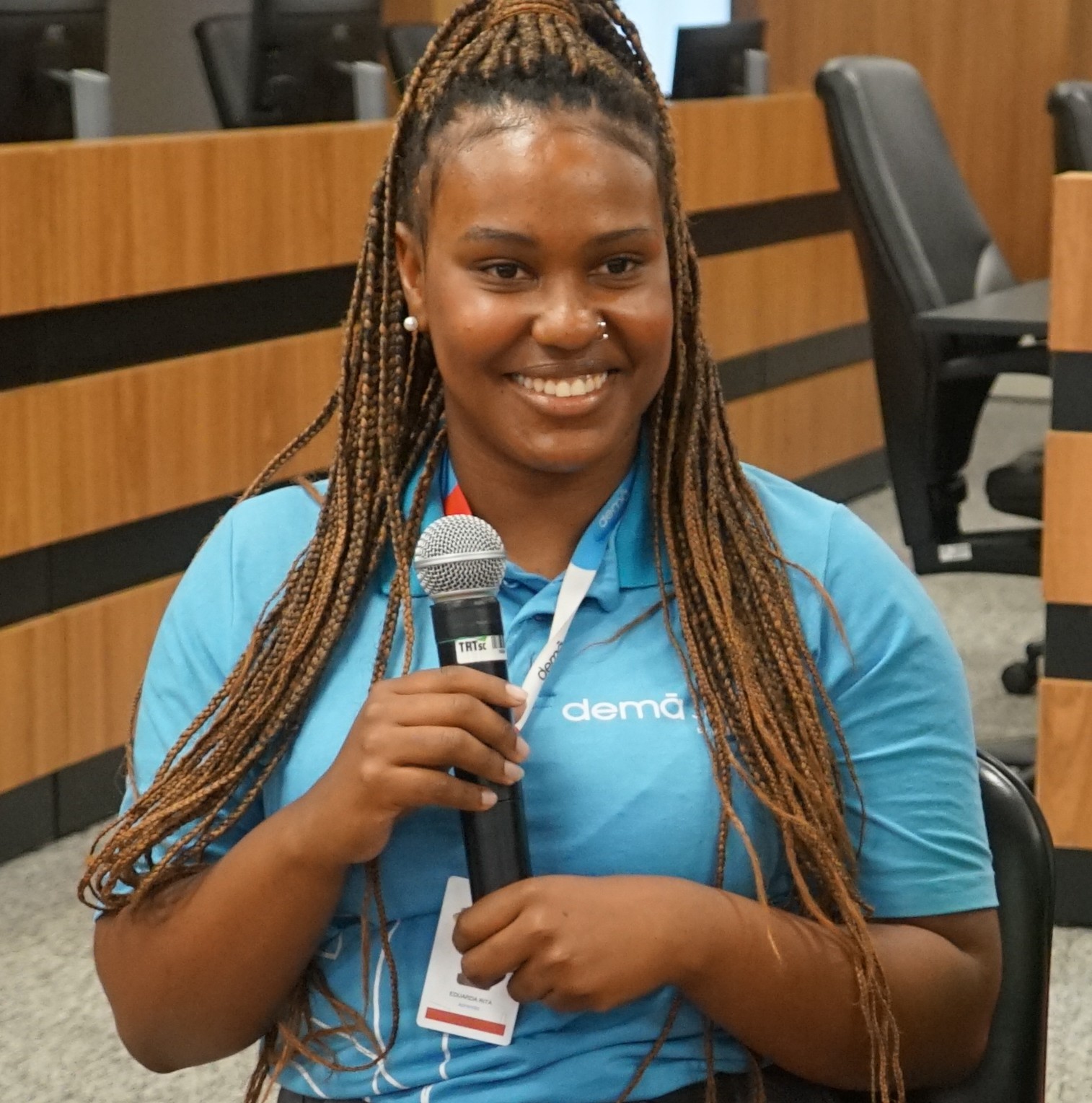 Jovem negra, sorridente, usando tranças