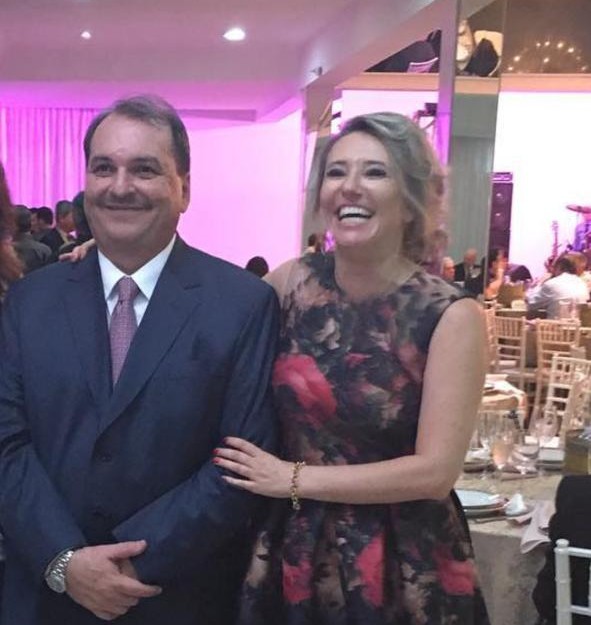 Foto de um homem de terno e gravata e uma mulher sorrindo, lado a lado