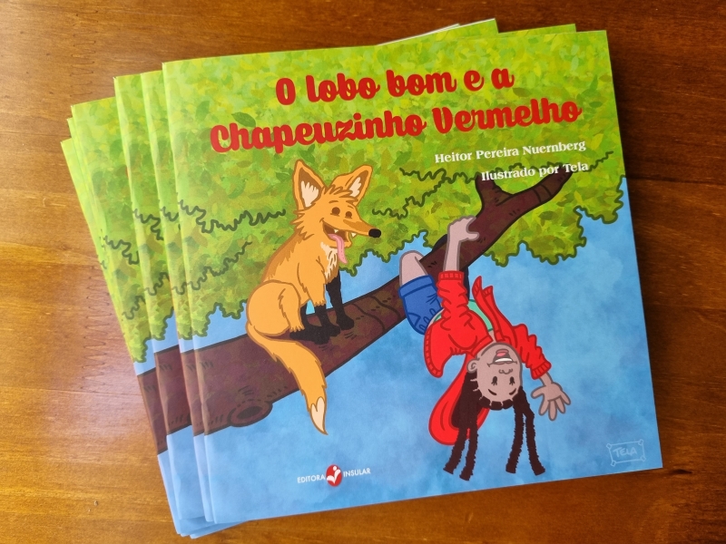 Para todos verem: Texto: "O lobo bom e a Chapeuzinho Vermelho. Heitor Pereira Nuernberg. Ilustrado por Tela. Editora Insular”. Ilustração: Capa do livro em que há um lobo e uma menina em um galho de árvore. O lobo está sentado e a menina está se pendurando de ponta cabeça.