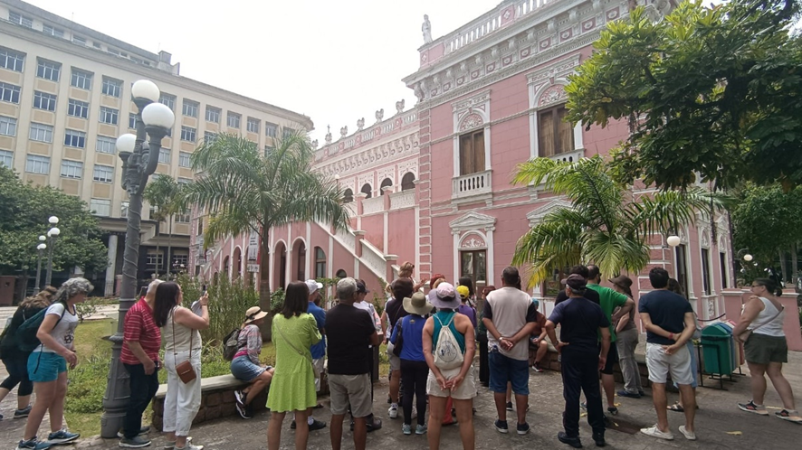 Foto com um grupo de pessoas observando um casarão antigo
