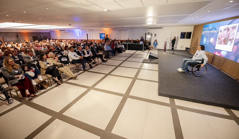 Auditório da Fiesc com cerca de 200 pessoas. No palco, um cadeirante se prepara para a palestra