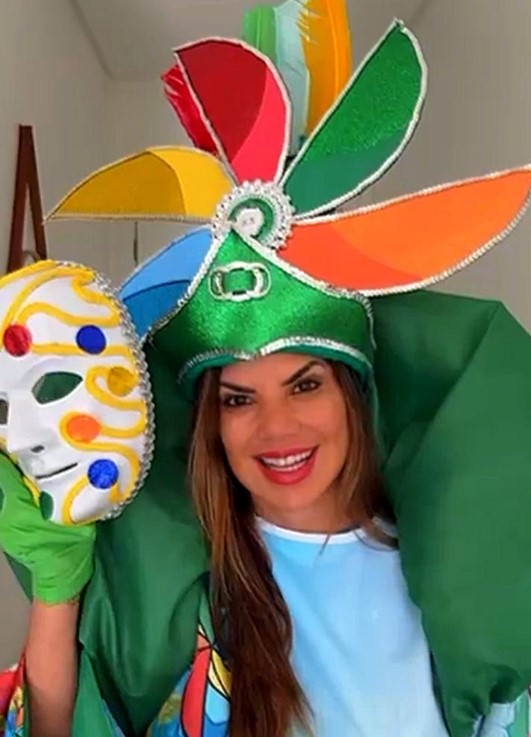 Foto de uma mulher segurando uma máscara veneziana e usando uma fantasia com um catavento na cabeça