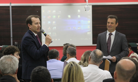 Foto tirada do fundo da plateia. À frente, juiz Ricardo Jahn e um reapresente de empresa