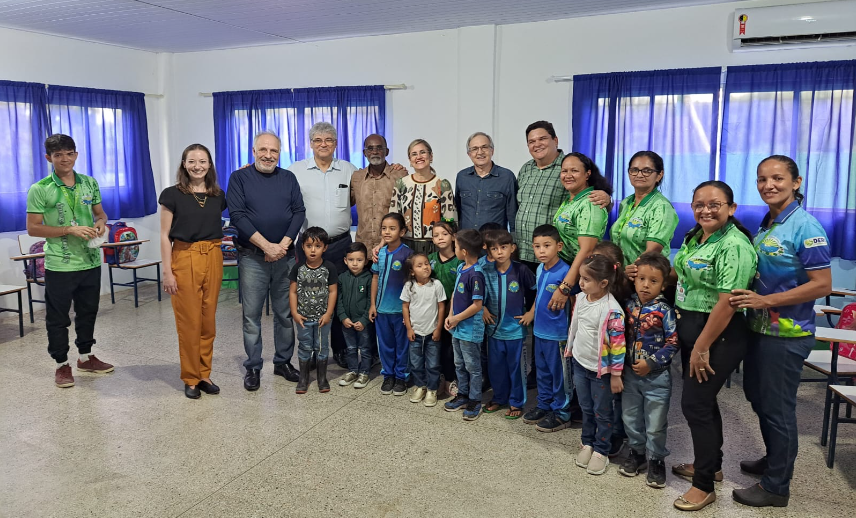 Grupo de 11 crianças de 5 a 8 anos e 12 adultos posam para foto dentro de uma sala de aula