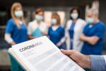 Imagem de uma equipe de médicos utilizando máscara de proteçao. À frente, um documento com a palavra coronavírus