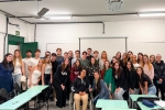 Grupo de estudantes reunidos em frente a um quadro branco posando para foto