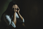 mulher humilhada encolhida em um quarto escuro