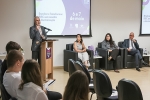 Homem branco de terno cinza e gravata em frente a um púlpito dando uma palestra