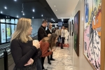 Grupo de 8 pessoas observando telas de Franklin Cascaes